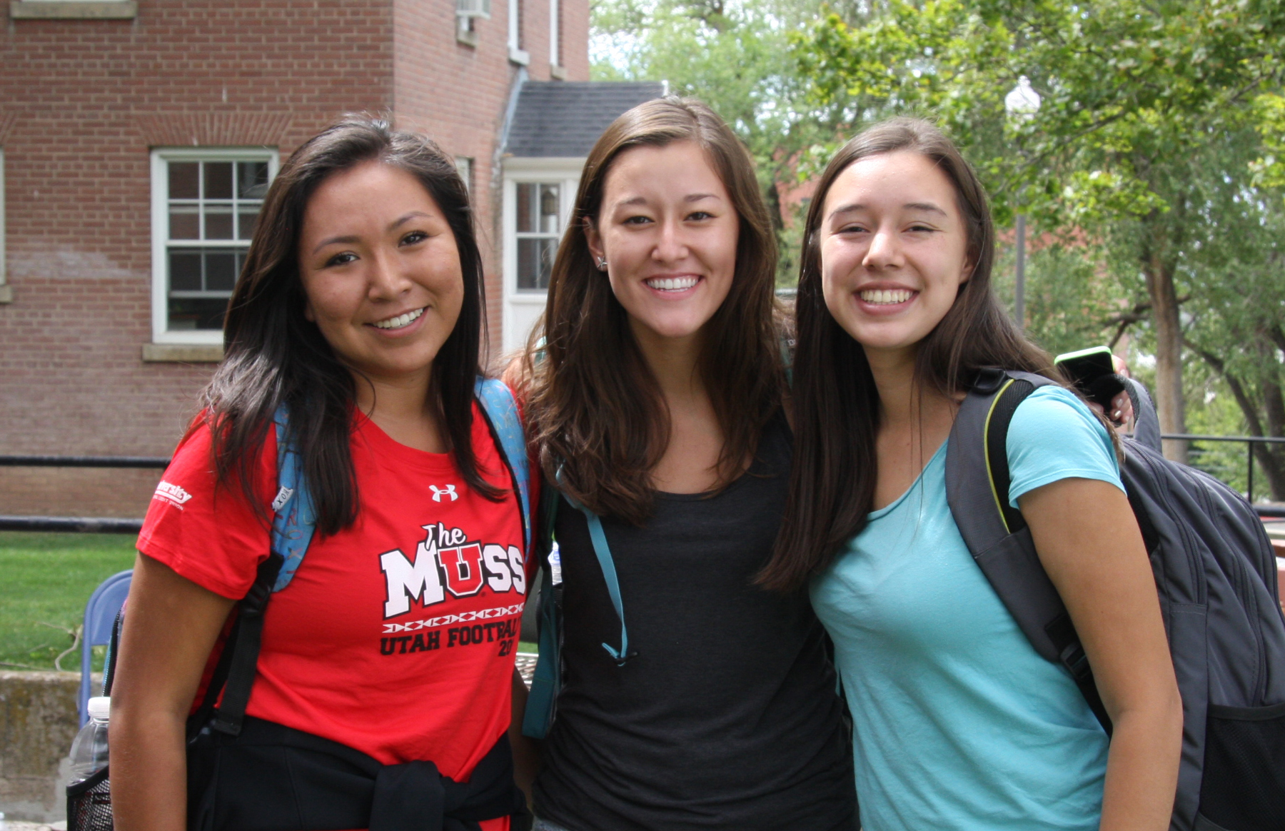 three students grouped together and smiling outside of the American Indian Resource Center