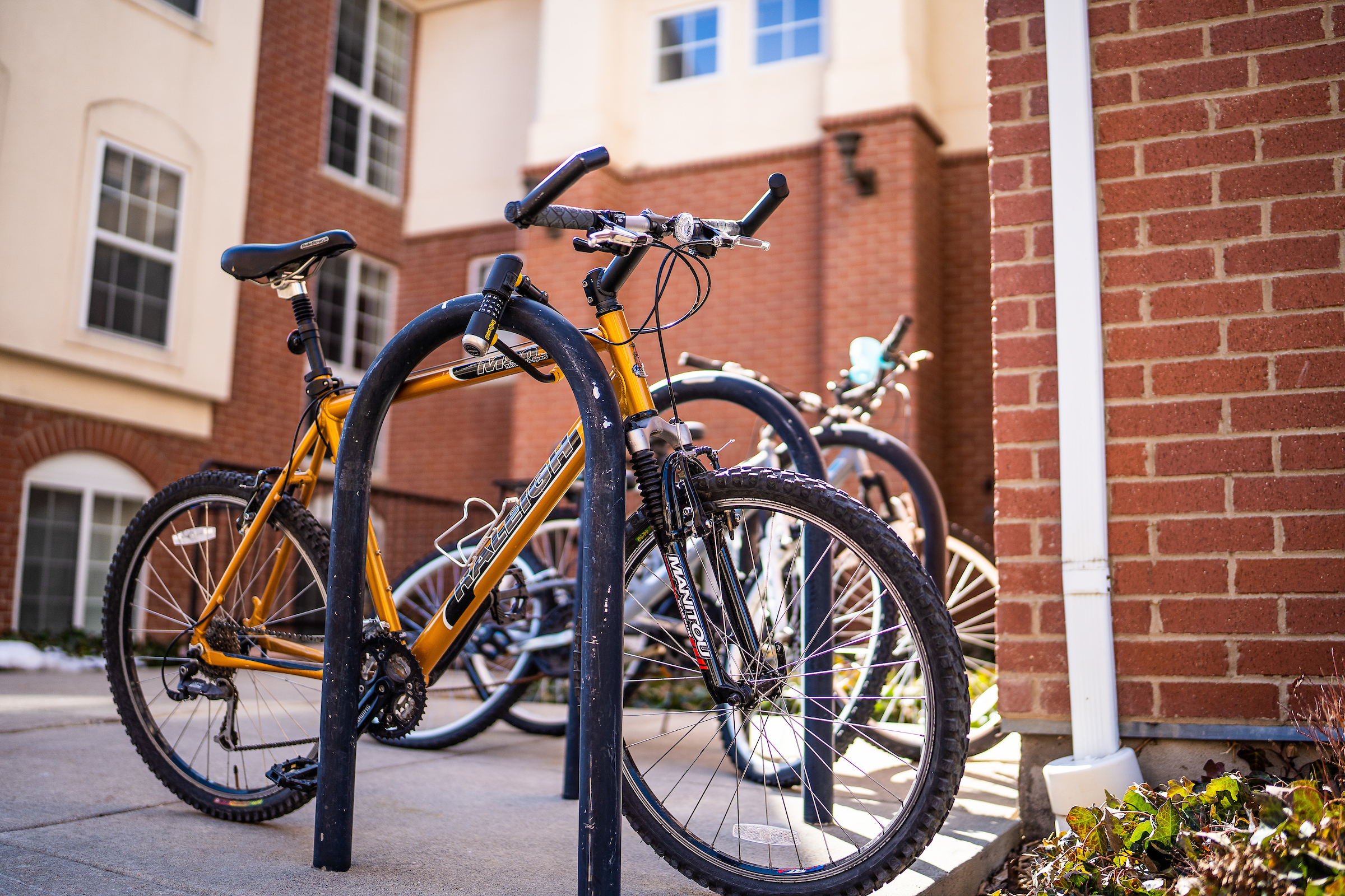 an orange bike locked on a rack outside of a residence hall at the University of Utah