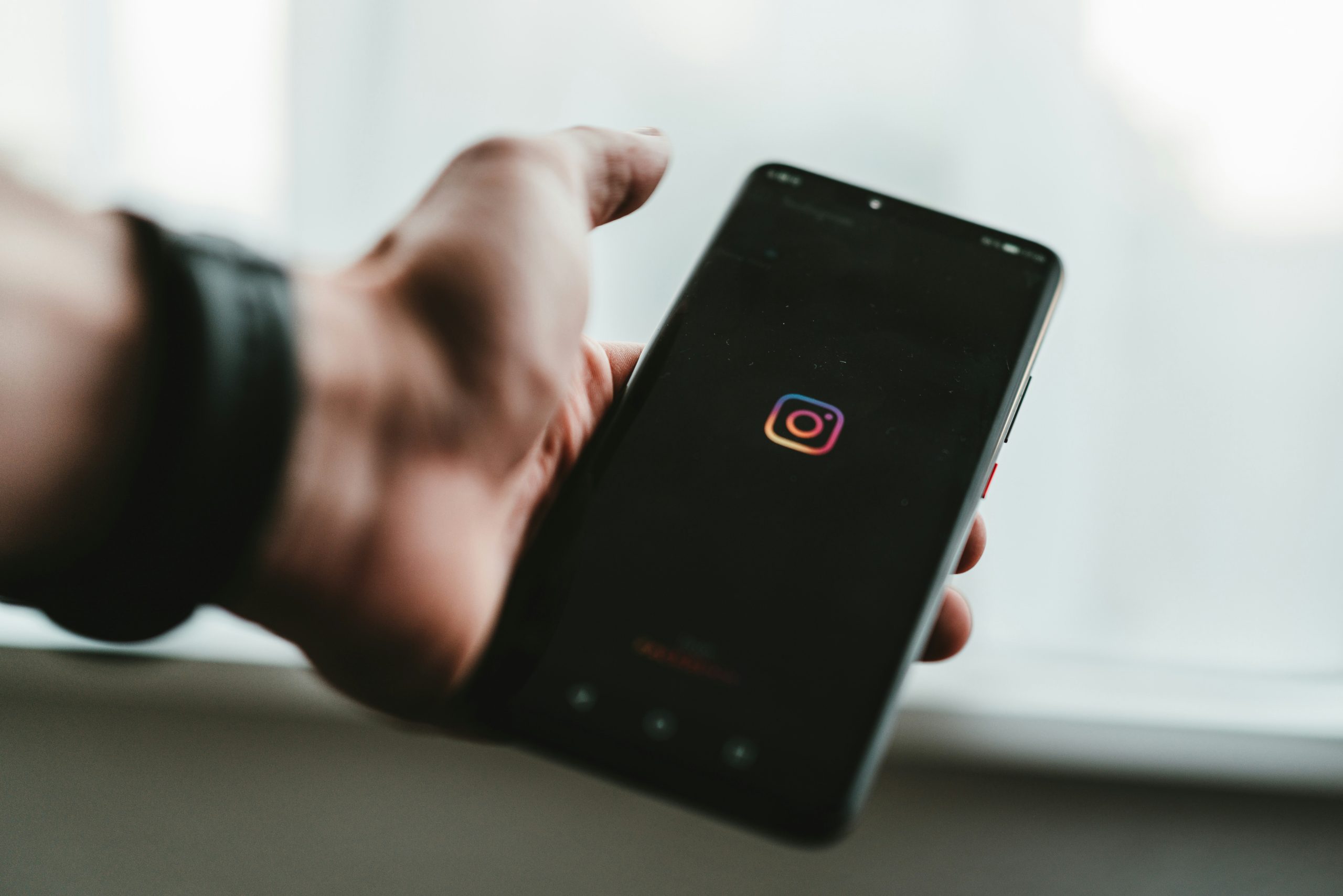 a hand holding a cellphone with the Instagram logo on the screen