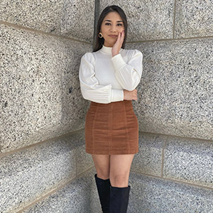 Leslie posing in the corner of a large granite building with her head in her hand 
