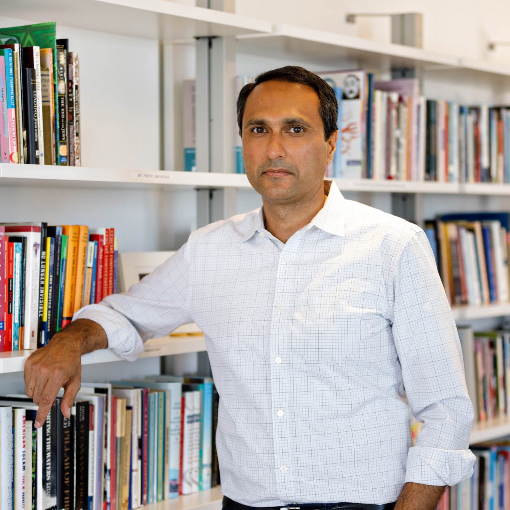 Eboo Patel posing in front of a bookcase
