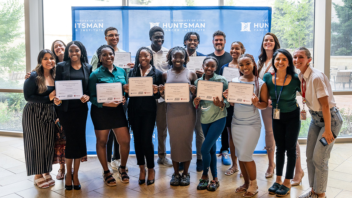 a group of student smile while holding certificates at the Huntsman Cancer Institute
