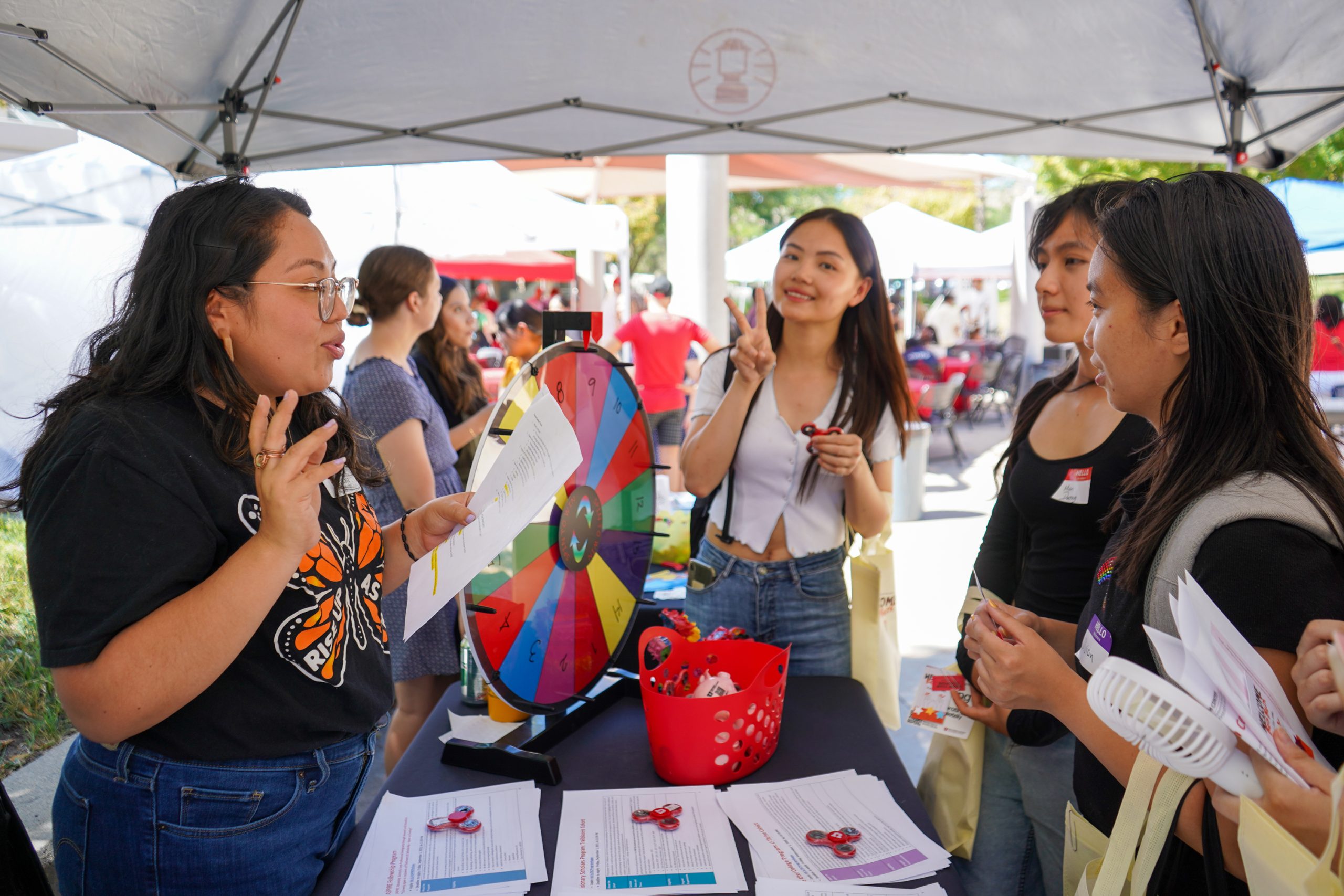 students talk with a program coordinator at a Welcome Back Bash table