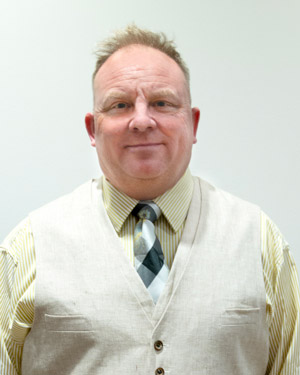 Chris Harris wearing a button-down shirt, vest, and checkered tie