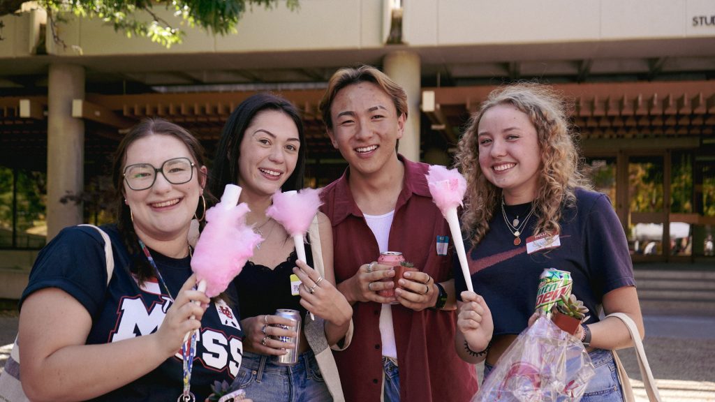 four students smile with cotton candy and soda