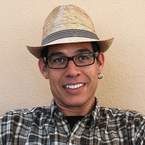 Jorge Rojas smiles in a hat and glasses