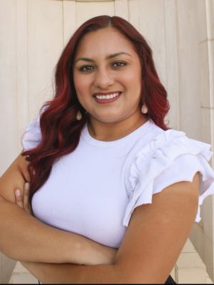portrait of Xochitl Juarez smiling with her arms crossed in front of her body