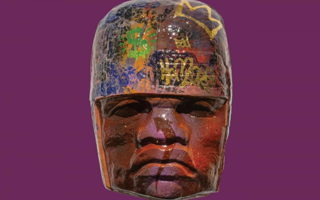 Large Mesoamerican sculpture of a head with graffiti on it.